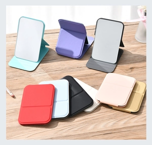 Various colors of foldable leather makeup mirrors displayed on a wooden tabletop