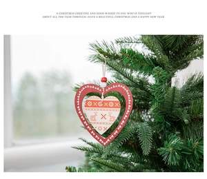 Detail of a red and white heart-shaped wooden Christmas ornament with reindeer patterns