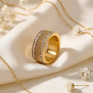 Detail of gold braided ring band with double row of cubic zirconia on silk background