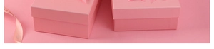 Detail of pink gift box with star embossed pattern and matching decorative ribbon