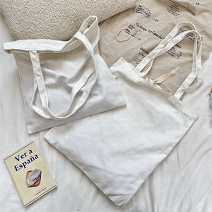 Detailed macro view of two minimalist plain white canvas tote bags with long shoulder straps