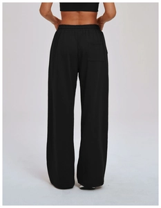 Detail view of the high-waisted elastic band and back pocket on black wide-leg sports pants