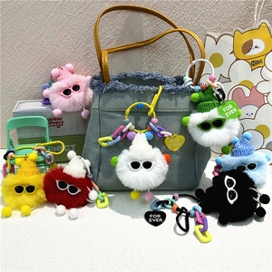 Porte-clés monstres en peluche colorés avec lunettes et bonnets sur fond denim
