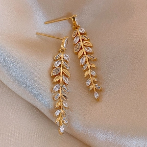 Gros plan détaillé de boucles d'oreilles feuilles dorées avec diamants sur soie champagne
