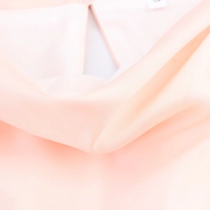 Detalle macro del escote con volantes en vestido de seda rosa con etiqueta talla S