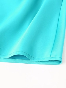Détail de l'ourlet de la robe en satin bleu montrant la texture et la couture fine