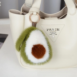 Détail d'un porte-clés avocat en peluche suspendu à un sac à main blanc élégant