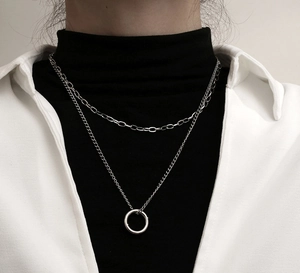 Detail of silver double-layered necklace with a minimalist ring pendant on black turtleneck