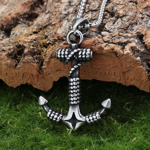 Detailed view of vintage silver anchor pendant on tree bark background