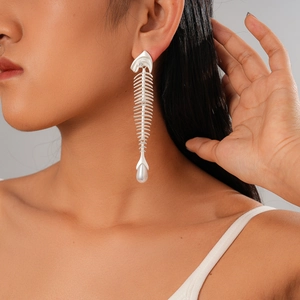 Exaggerated silver fishbone earrings with pearls and zircons shown on a model