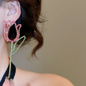Close-up of elegant tulip earrings with pink and green rhinestones worn by a model