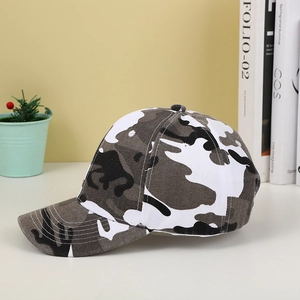 Side view of camouflage baseball cap with adjustable strap on a clean home desk