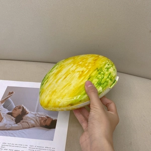 Detail of egg-shaped marble clutch with smooth yellow and green gradient resin finish