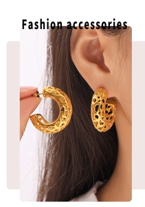 Detailed close-up of hollow C-shaped gold hoop earrings with textured organic pattern