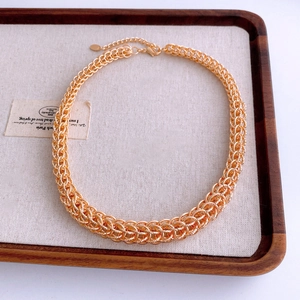 Gros plan d'un collier chaîne chunky doré avec fermoir mousqueton sur un plateau en bois