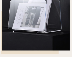 Close-up of clear acrylic magazine rack with metal base on a black display stand