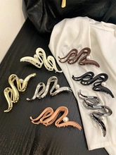 Detail showing seven colors of large resin shark hair clips on a black surface