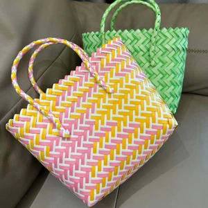 Handwoven colorful basket bags in pink and green patterns on a brown leather surface