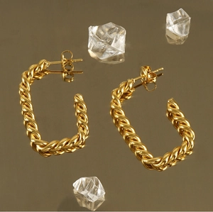 Gros plan de créoles torsadées plaquées or 18 carats avec reflet miroir luxueux