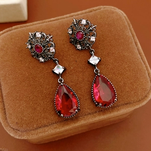 Détail de boucles d'oreilles vintage avec pierres rouges en poire sur velours marron