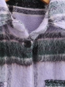 Close-up detail of purple plaid wool coat with fuzzy texture and black resin button