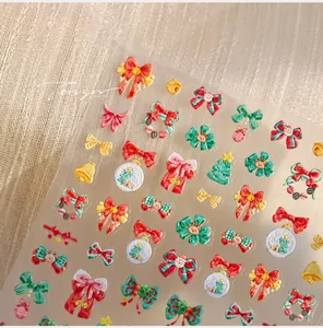 Macro shot of 3D embossed Christmas nail art stickers with red bows and holly designs