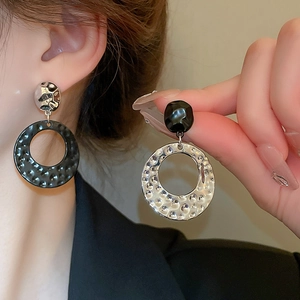 Detail of silver drop earrings with black geometric stud and hammered metal texture