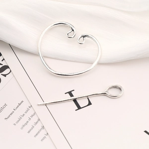 Detail view of a vintage silver Viking brooch pin on elegant white silk and magazine