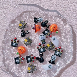 Detailed macro shot of resin Halloween charms featuring ghosts and pumpkins on glass