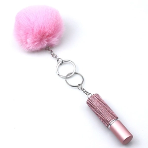 Detail of pink faux fur pompom and rhinestone encrusted lipstick charm keychain set