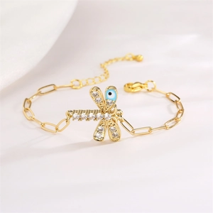 Detail of golden dragonfly bracelet with evil eye motif and cubic zirconia on paperclip chain