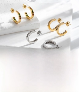 Detailed view of titanium steel C-shape earrings with zircon inlay in gold and silver