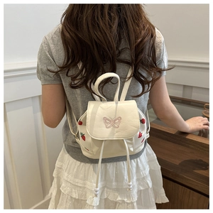 Detail of white backpack with pink butterfly embroidery and red strawberry prints