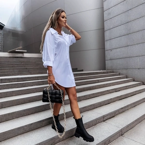 Women's white long sleeve oversized button-up shirt dress with boots and chain bag