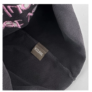Dettaglio della trama del cappello in maglia grigio scuro e etichetta interna