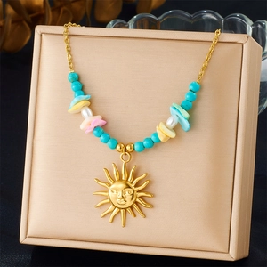 Gold stainless steel necklace with sun pendant and colorful irregular beads on a cushion