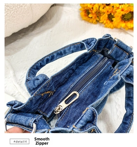 Close-up of the smooth metal zipper and durable blue washed denim fabric on the handbag