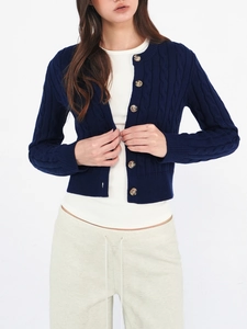 Navy cable knit wool cardigan with amber buttons on a model in a white studio setting