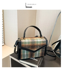 Detail der grünen Tweed-Umhängetasche mit schwarzem Lederbesatz und Goldbeschlägen