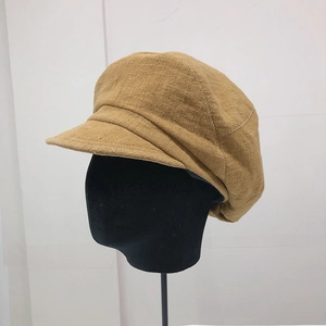 Dettaglio del cappello newsboy cammello con trama in lino grezzo e cuciture vintage