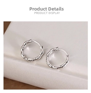 Detailed view of silver bamboo joint hoop earrings on a marble stone display