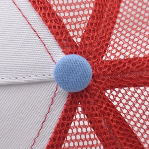 Close-up of the red mesh and white cotton top of the baseball cap with blue button detail