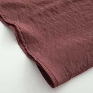 Detail of dark red chiffon fabric showing fine texture and clean stitching craftsmanship