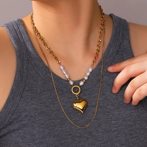 Double layer gold necklace with pearls and heart pendant worn by a female model