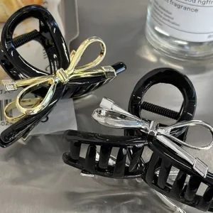 Set of black hair claw clips with metallic gold and silver bow accents for elegant hairstyles