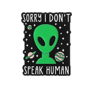 Detailed close-up of green alien enamel pin with Sorry I Don't Speak Human text