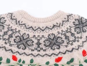 Detail of round neckline and floral embroidery on beige Nordic style knit sweater