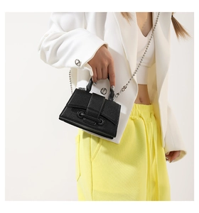 Detail of mini black lychee leather handbag featuring a silver beaded chain strap and handle