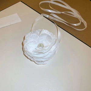 Macro detail of white lace fabric camellia flower necklace with long satin ribbons