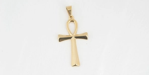 Macro shot of polished gold Ankh cross pendant symbolizing life on textured background